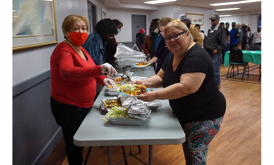 Commons Senior Christmas Luncheon 12-6-2022 Serving food and looking at camera for web
