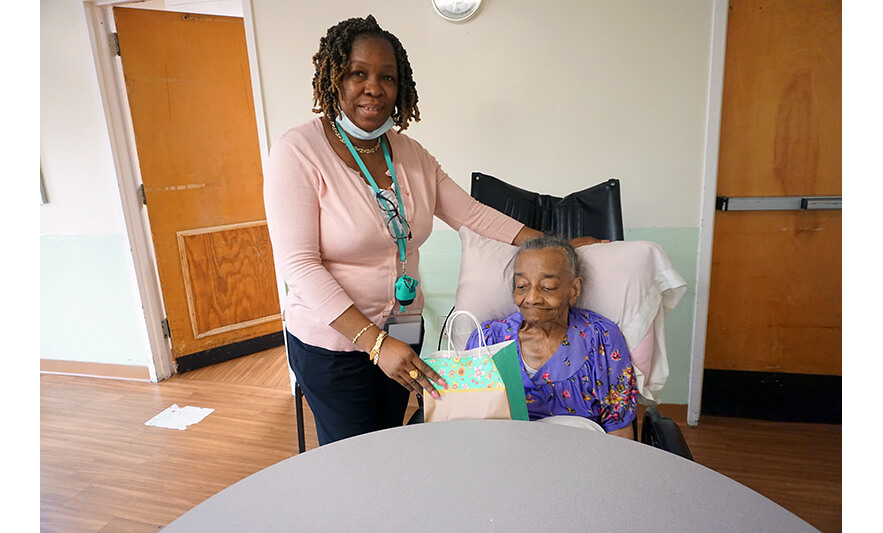 Extended Care Adopt-a-Resident Day 5-11-2022 Yonette Semple giving gift bag to woman for web