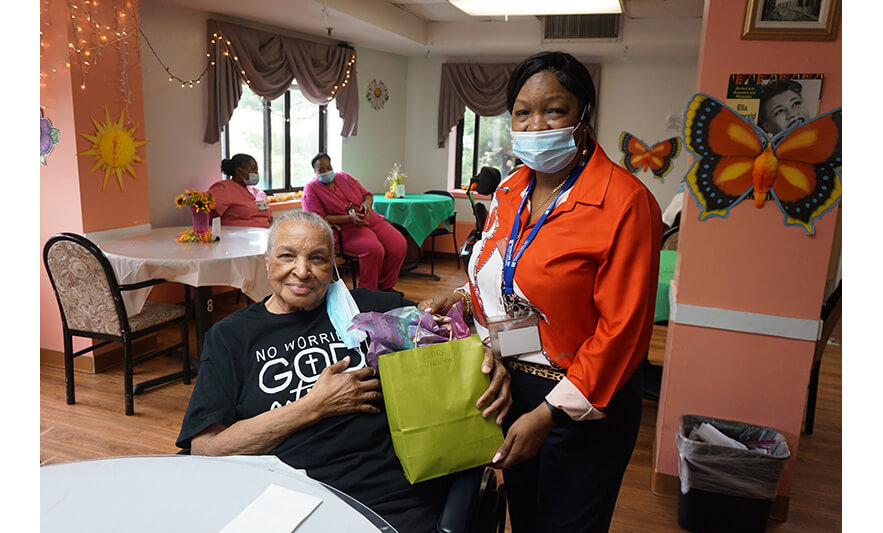 Extended Care Adopt-a-Resident Day 5-15-2025 Yonette Semple handing gift to woman for web